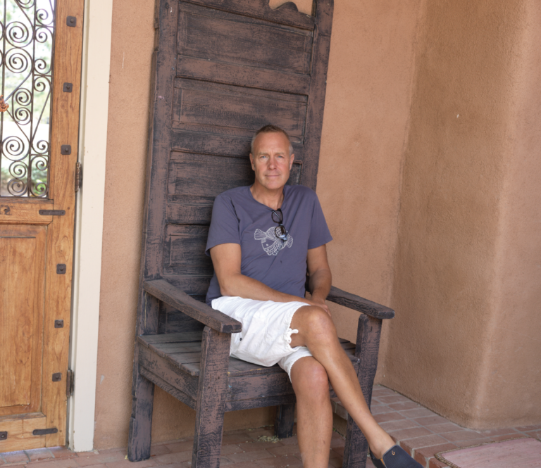 Jamie Lenfestey, Santa Fe concert promoter, sits in a large wooden chair looking at the camera